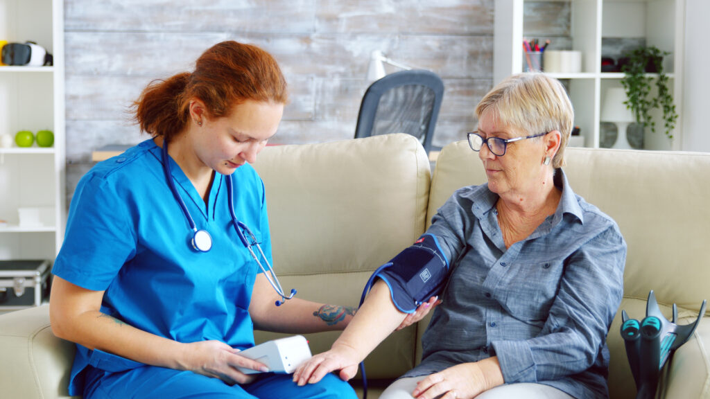 Female doctor taking blood pressure of senior woman- Vitals Health Care