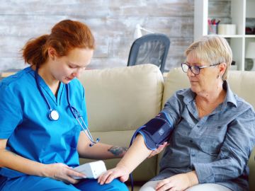 Female doctor taking blood pressure of senior woman- Vitals Health Care